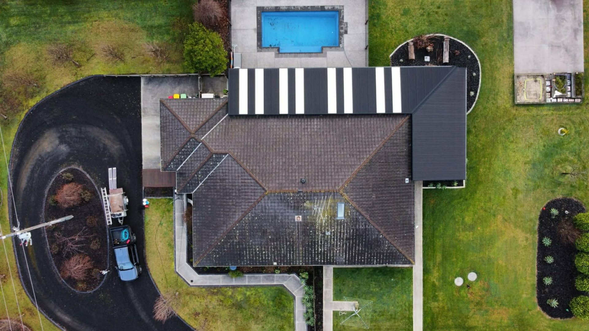 Aerial view of a large home's weathered tile roof before restoration