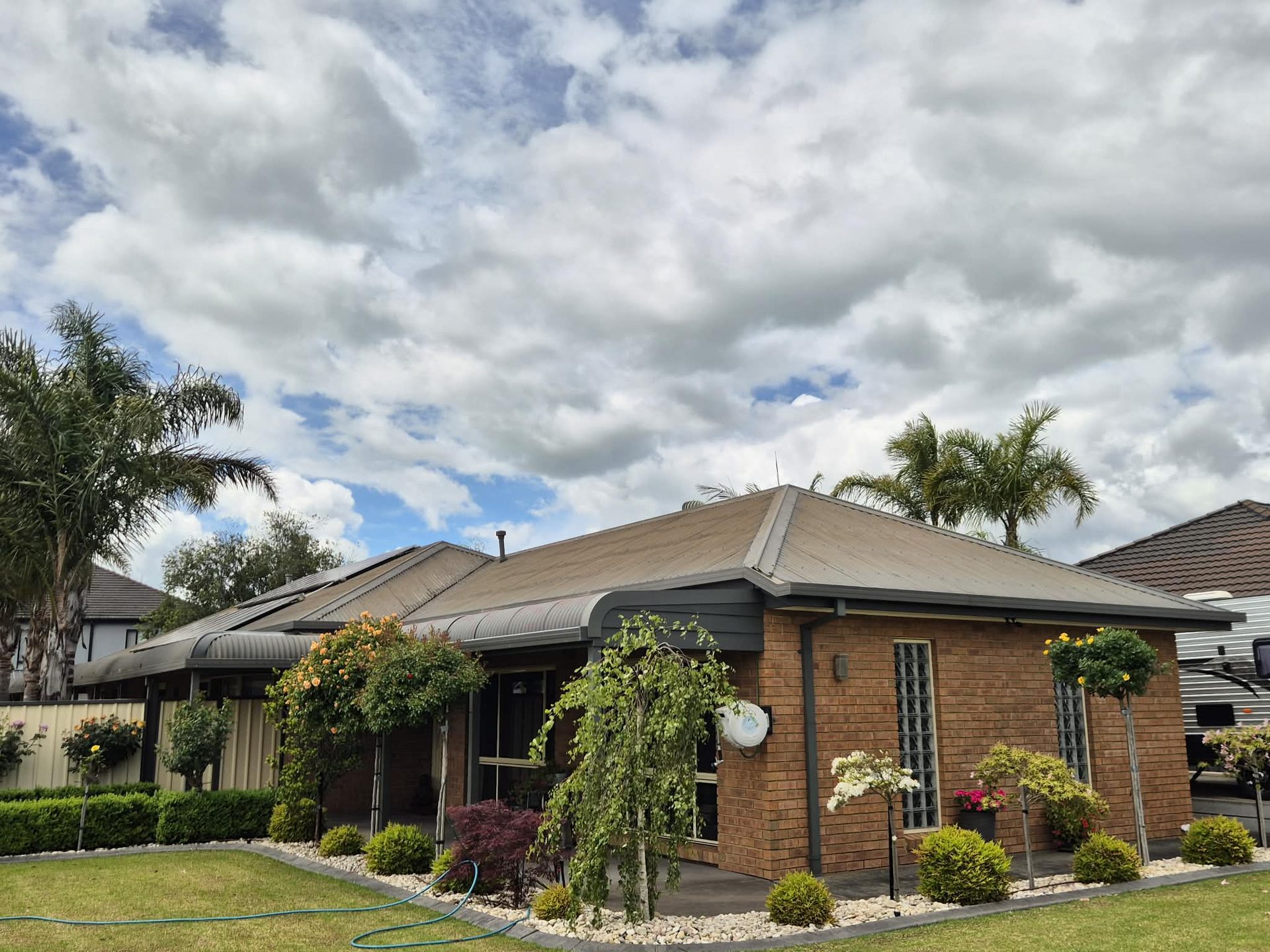 Suburban brick home with faded khaki Colorbond — before